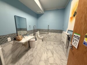 Photo shows a spacious, well-lit restroom with bars near the toilet and space for a baby-changing station.